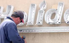 Retrofit Signs- Green Signs & Lighting Picture of man retrofitting sign